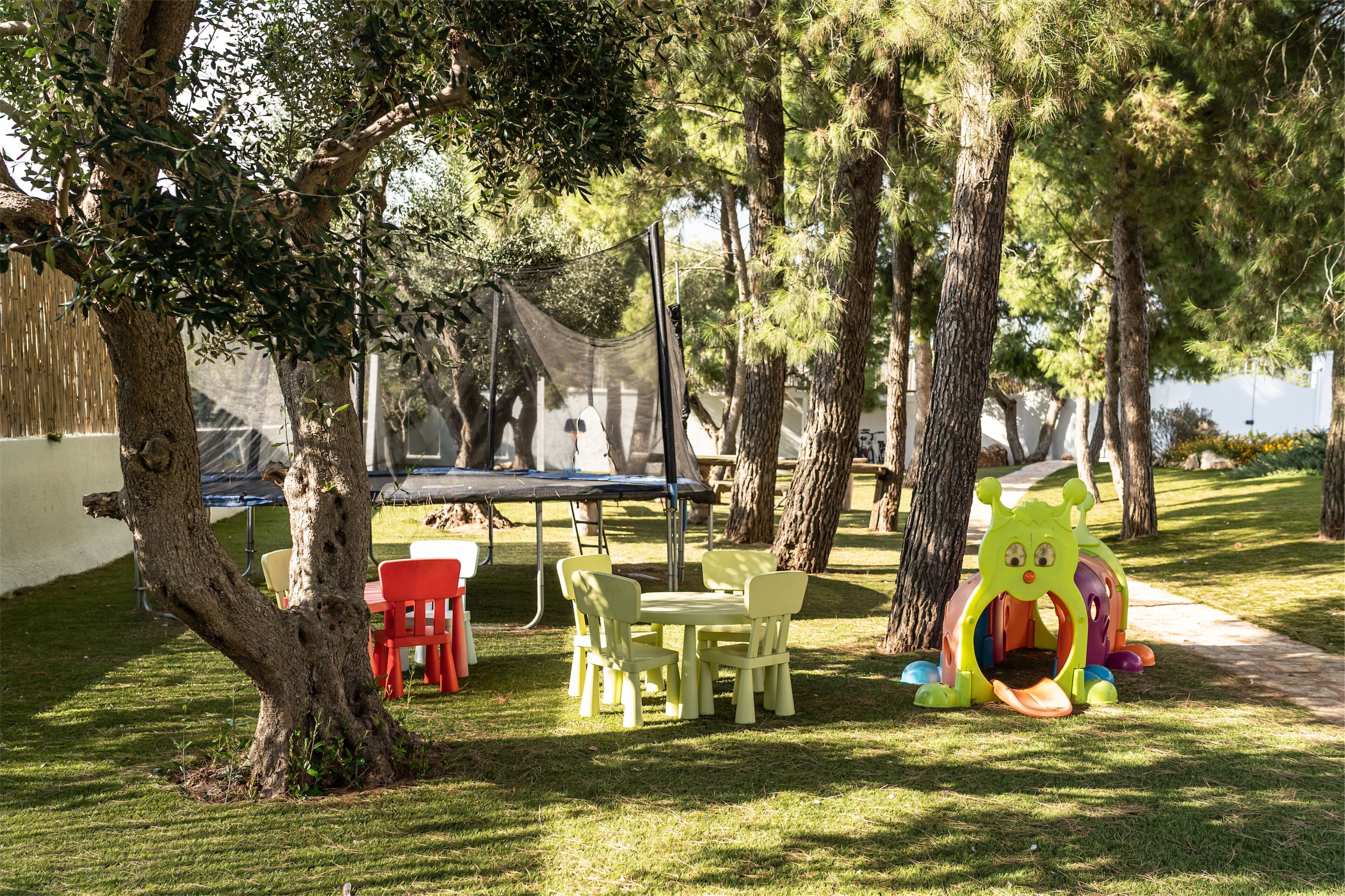 Un parque con mesas de picnic, un trampolín y una estructura de juegos infantiles.