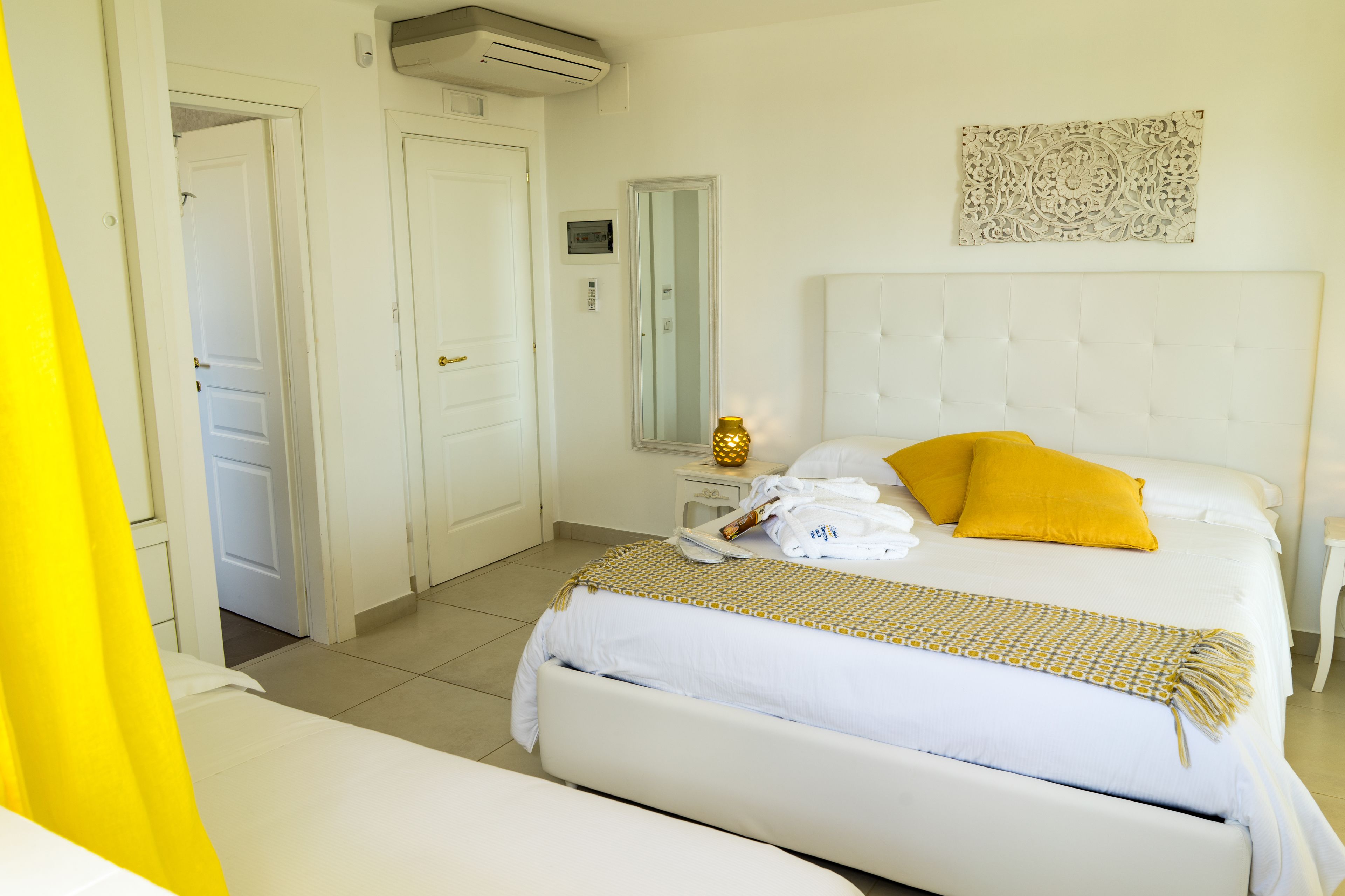 A hotel room with a large bed, a bedside table, a mirror, and a wall-mounted artwork.