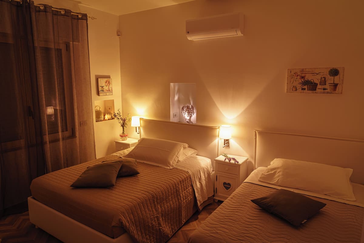Ein Hotelzimmer mit zwei Betten, einem Nachttisch mit Lampe, einer Klimaanlage und einem Wandbild.