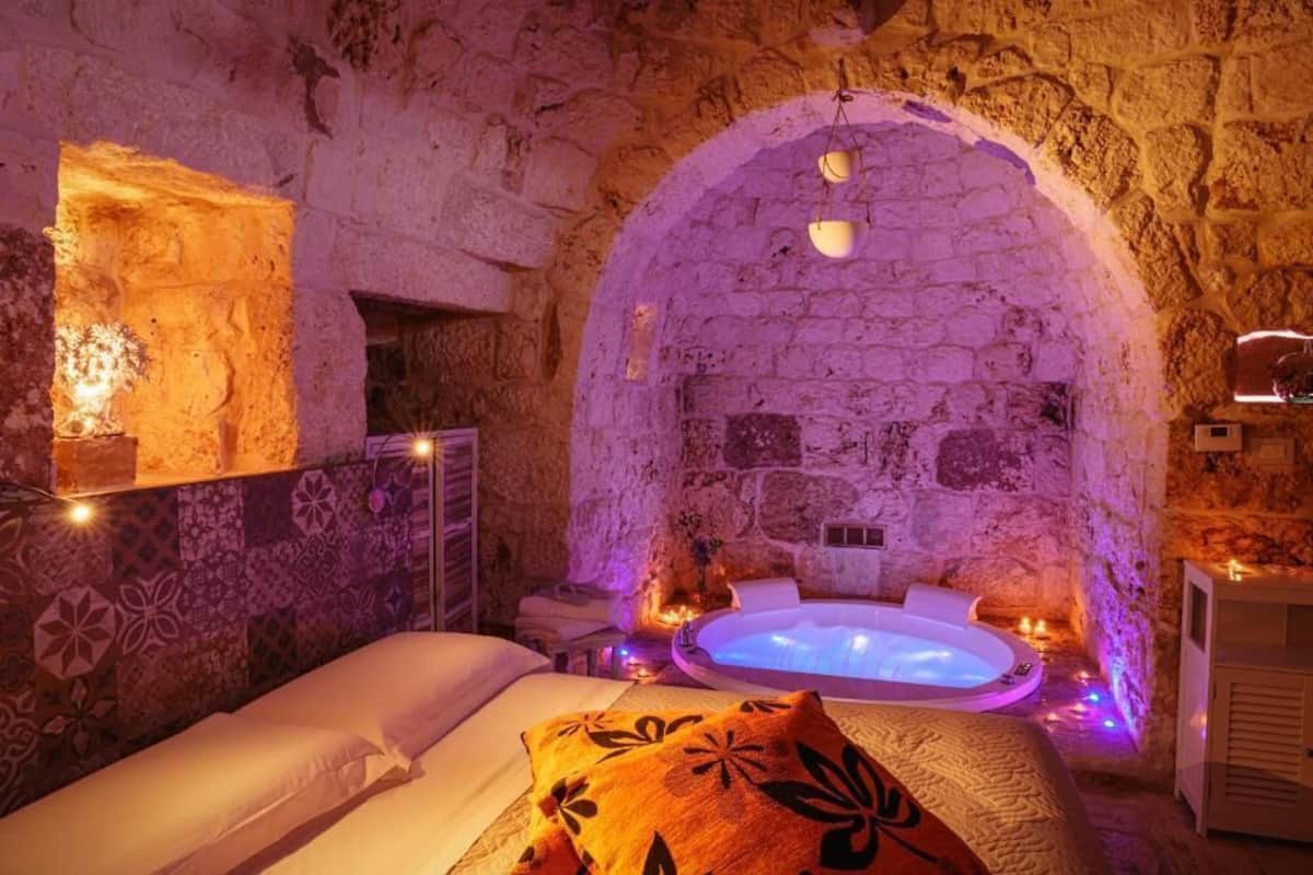 Ein Zimmer mit Stehwänden, einem Bett, einer Badewanne und einem kleinen Tisch mit Kerzen.