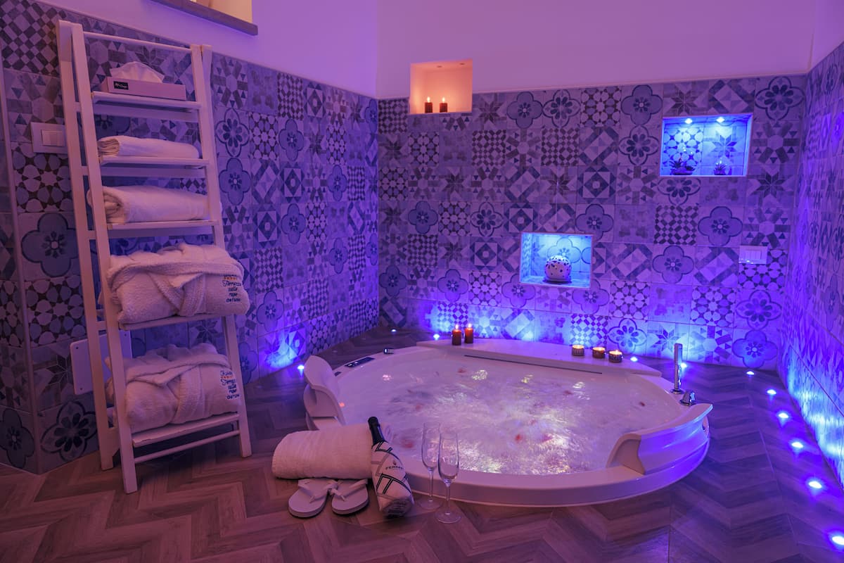 Ein Wellnessraum mit einer großen Badewanne, einem Handtuchhalter und einer Champagnerflasche.
