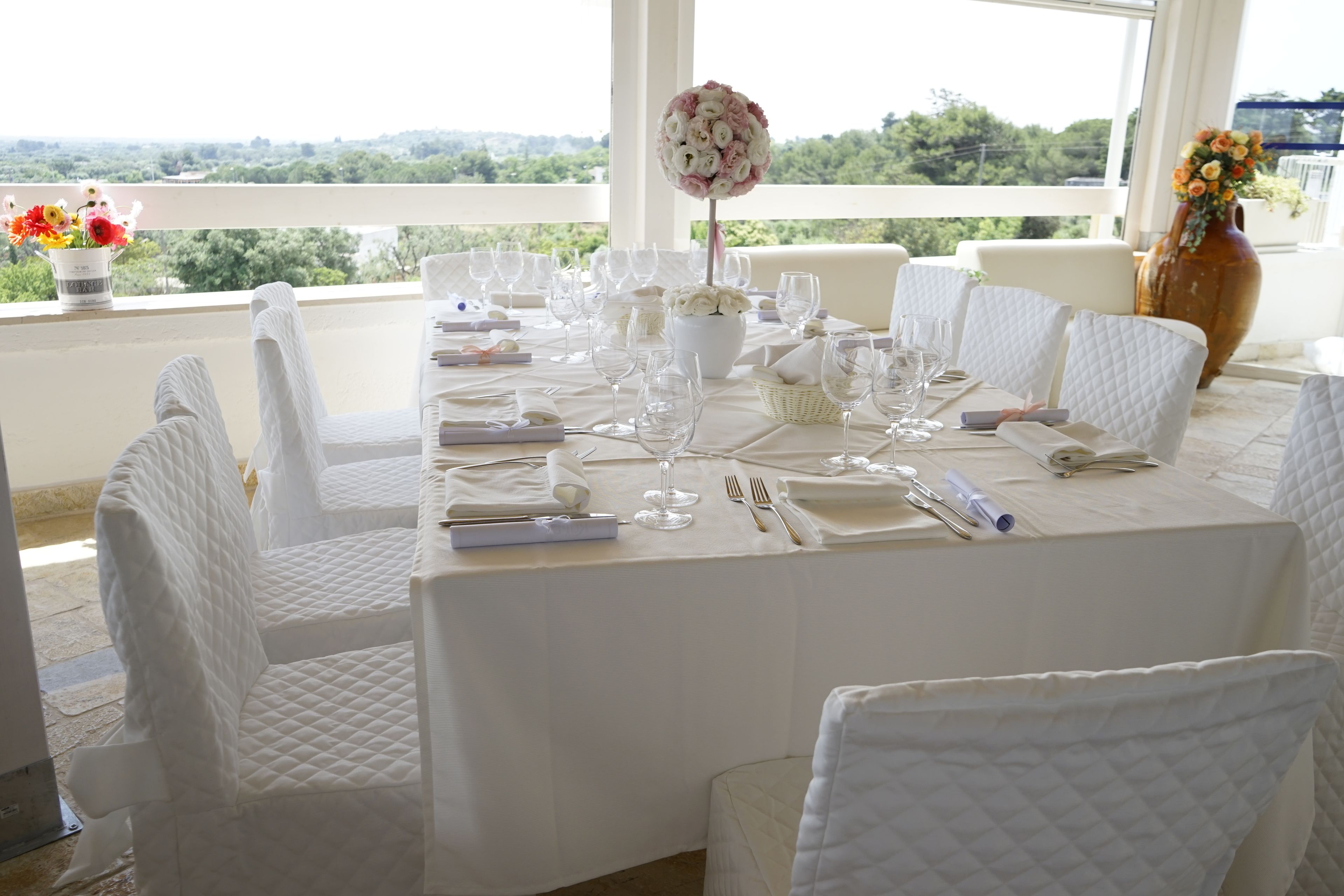 A table set for a formal event with white tablecloths, glassware, and chairs.