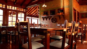 Un restaurante con mesas y sillas de madera, paredes de ladrillo y un reloj grande.