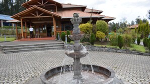 Una fuente de piedra en un patio, con un edificio de madera al fondo.