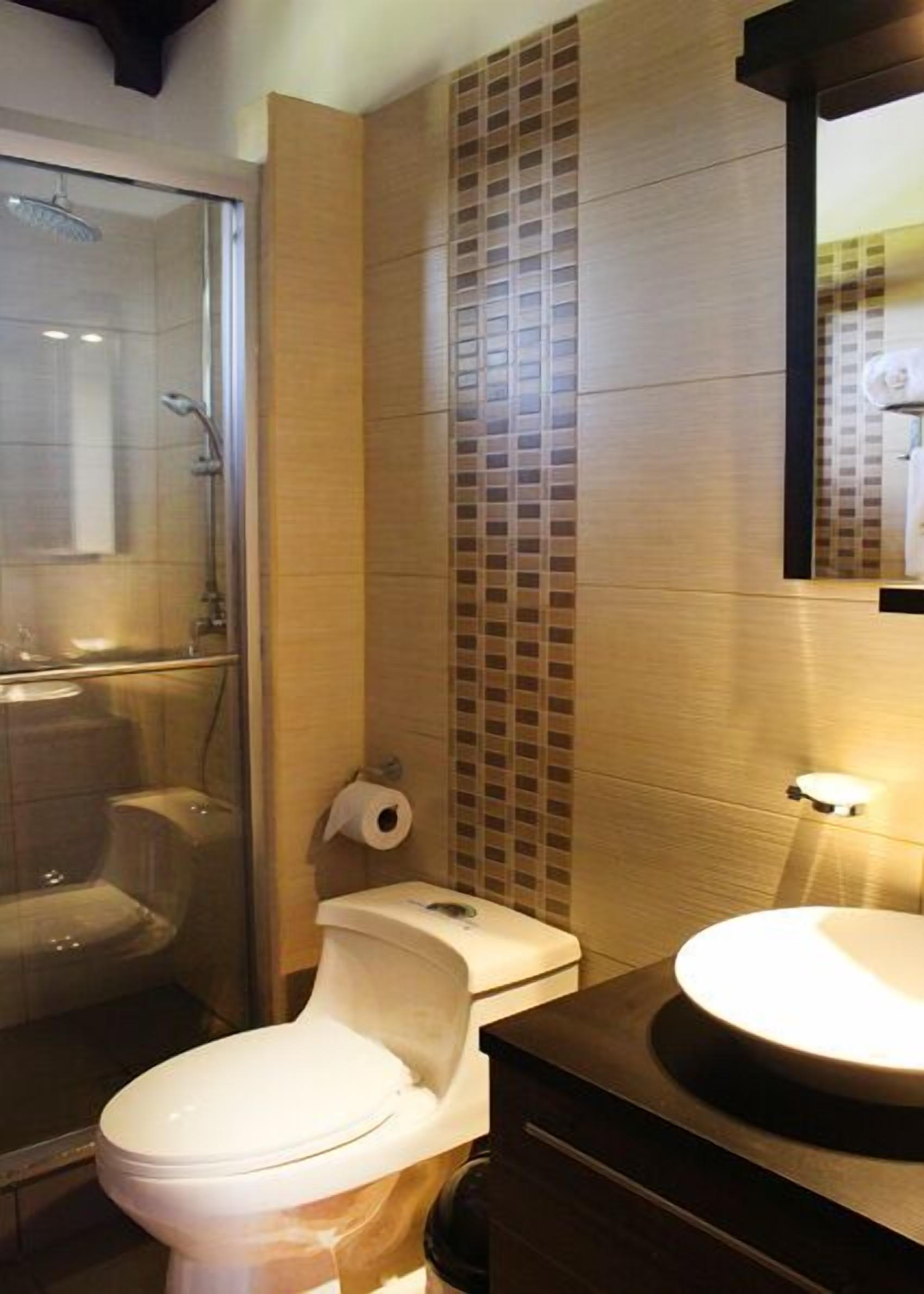 A bathroom with a glass-enclosed shower, a toilet, and a sink.