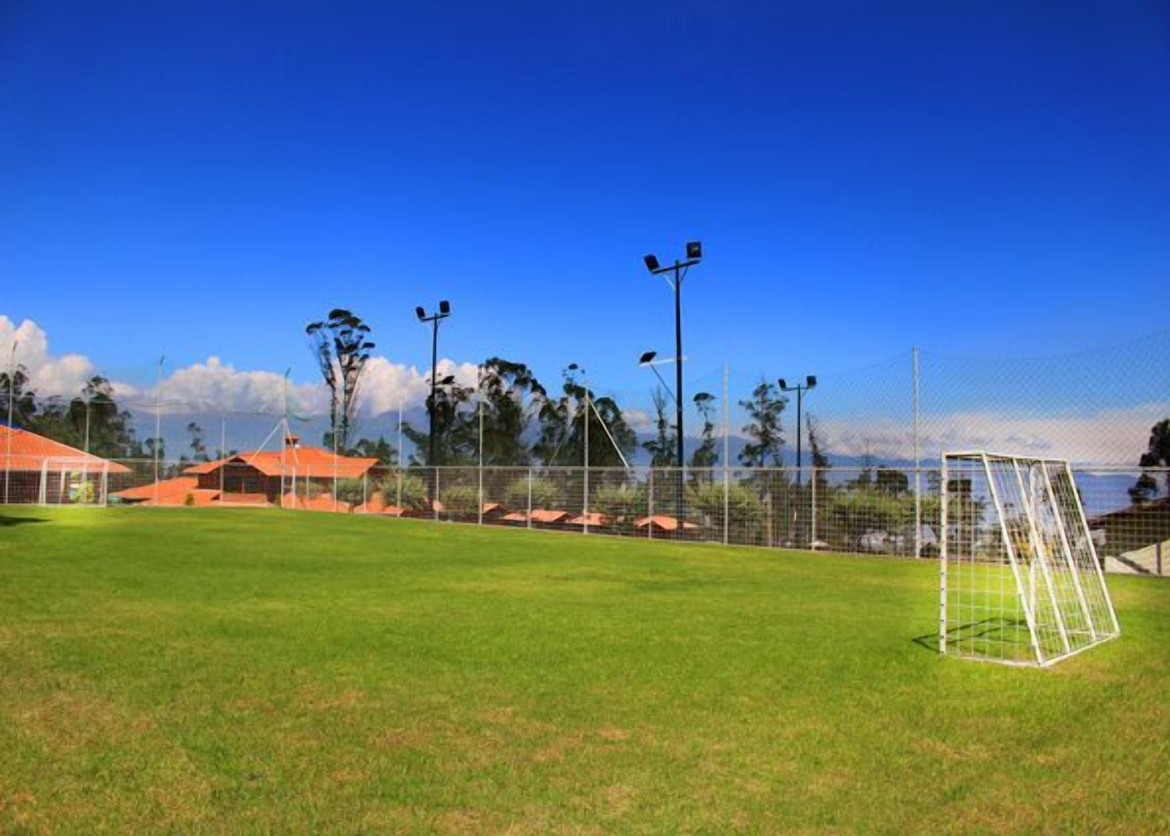 A soccer field with goalposts, floodlights, and a fence.