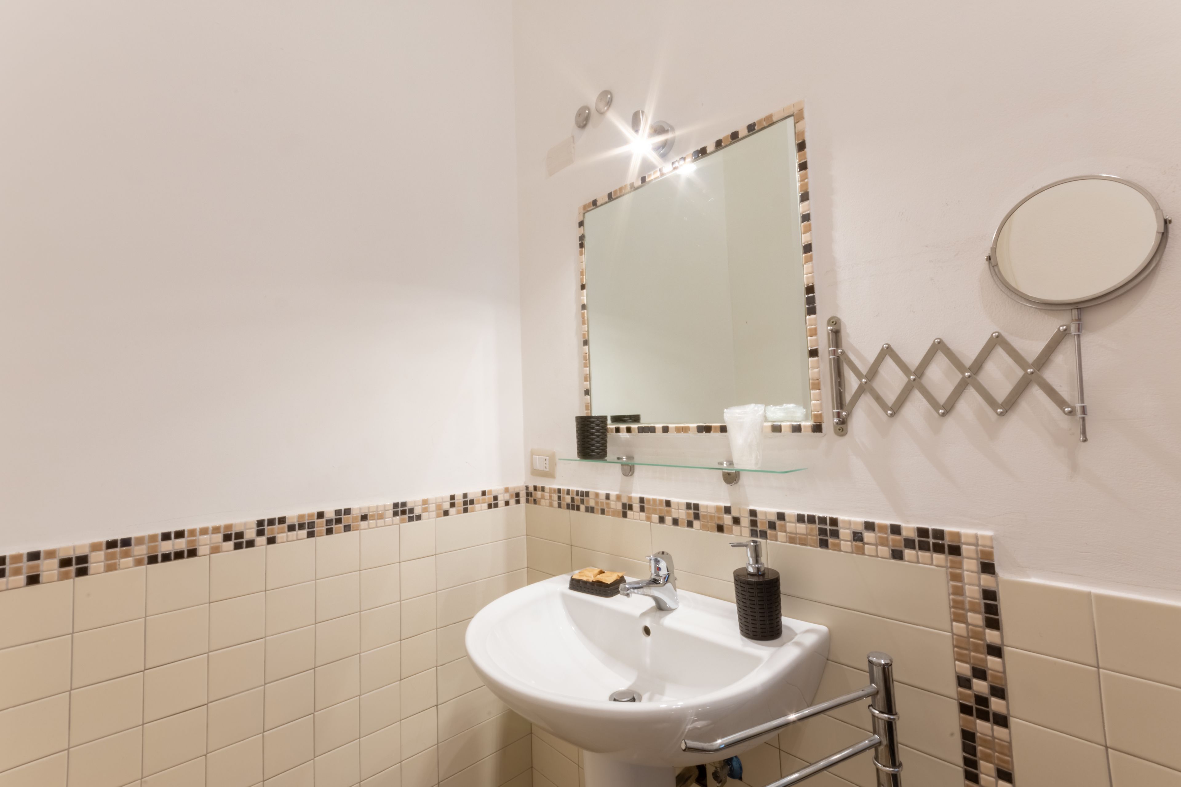 A bathroom with a white sink, a mirror, and a towel rack.