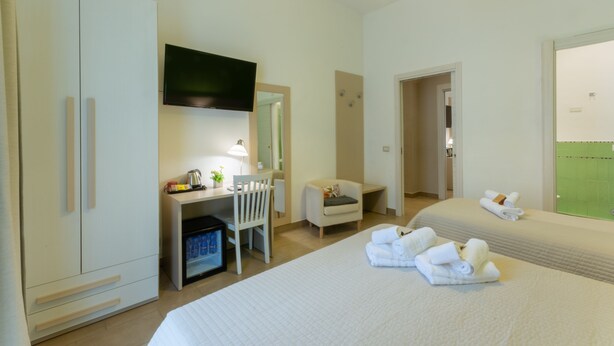 A hotel room with a bed, a desk with a chair, a television, and a wardrobe. - B&B Cairoli (Messina)