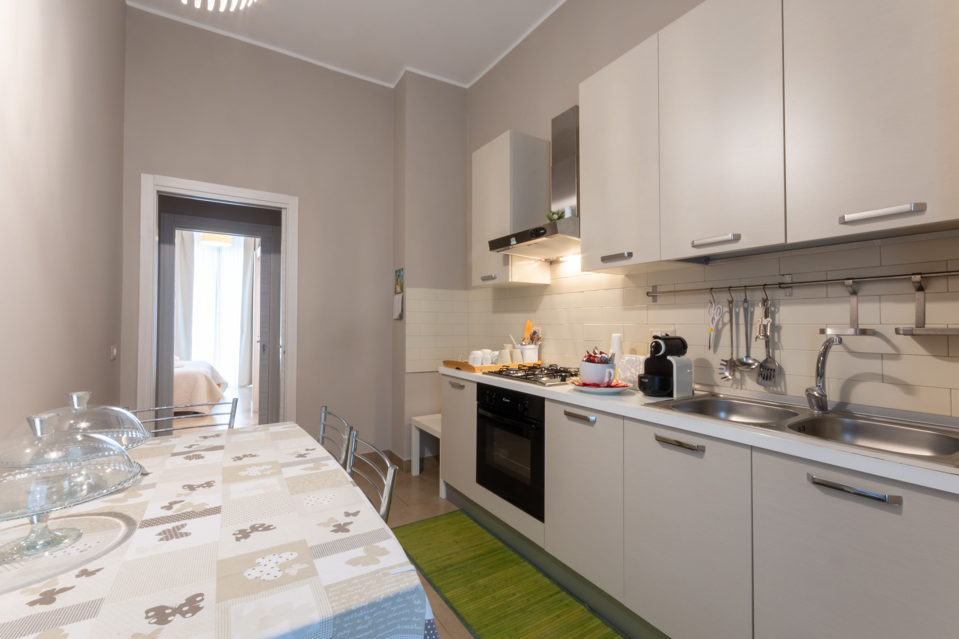 A modern kitchen with white cabinets, a stainless steel sink, and a dining area with a table set for two.