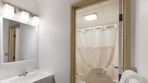 A bathroom with a white sink, mirror, and shower curtain. - SureStay by Best Western Presque Isle (Presque Isle)
