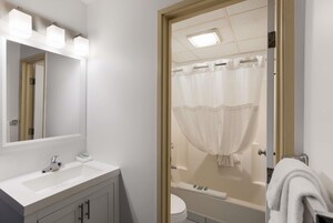 Un baño con lavamanos blanco, espejo y cortina de ducha.