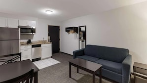 A compact living space with a kitchenette, a sofa, a dining table, and a small coffee table. - SureStay by Best Western Presque Isle (Presque Isle)
