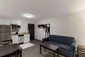 Un espacio habitable compacto con kitchenette, un sofá, una mesa de comedor y una pequeña mesa de centro.