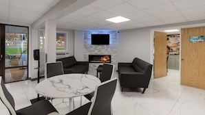 A modern lounge area with a fireplace, comfortable seating, and a flat-screen TV. - SureStay by Best Western Presque Isle (Presque Isle)