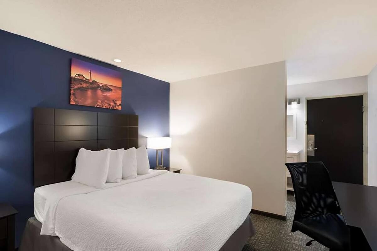 Ett hotellrum med en stor säng, ett skrivbord och en stol.