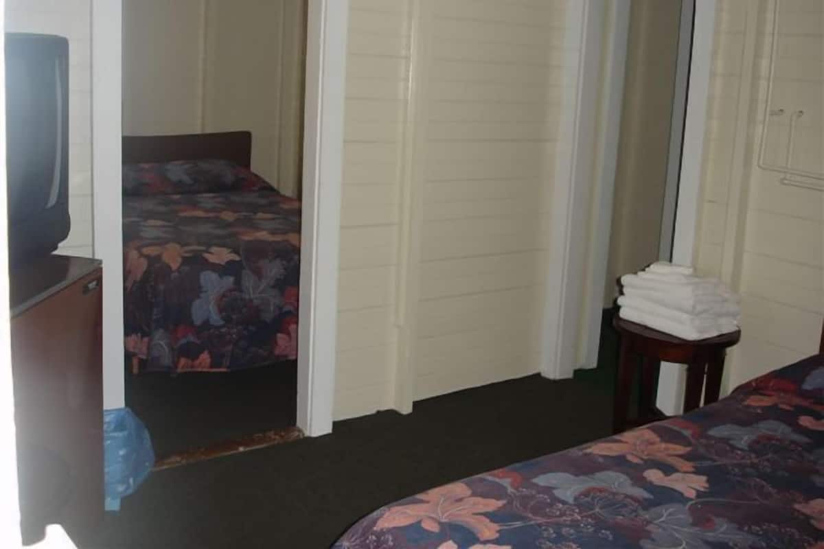 A bedroom with a bed, a small table with towels, and a mirror.
