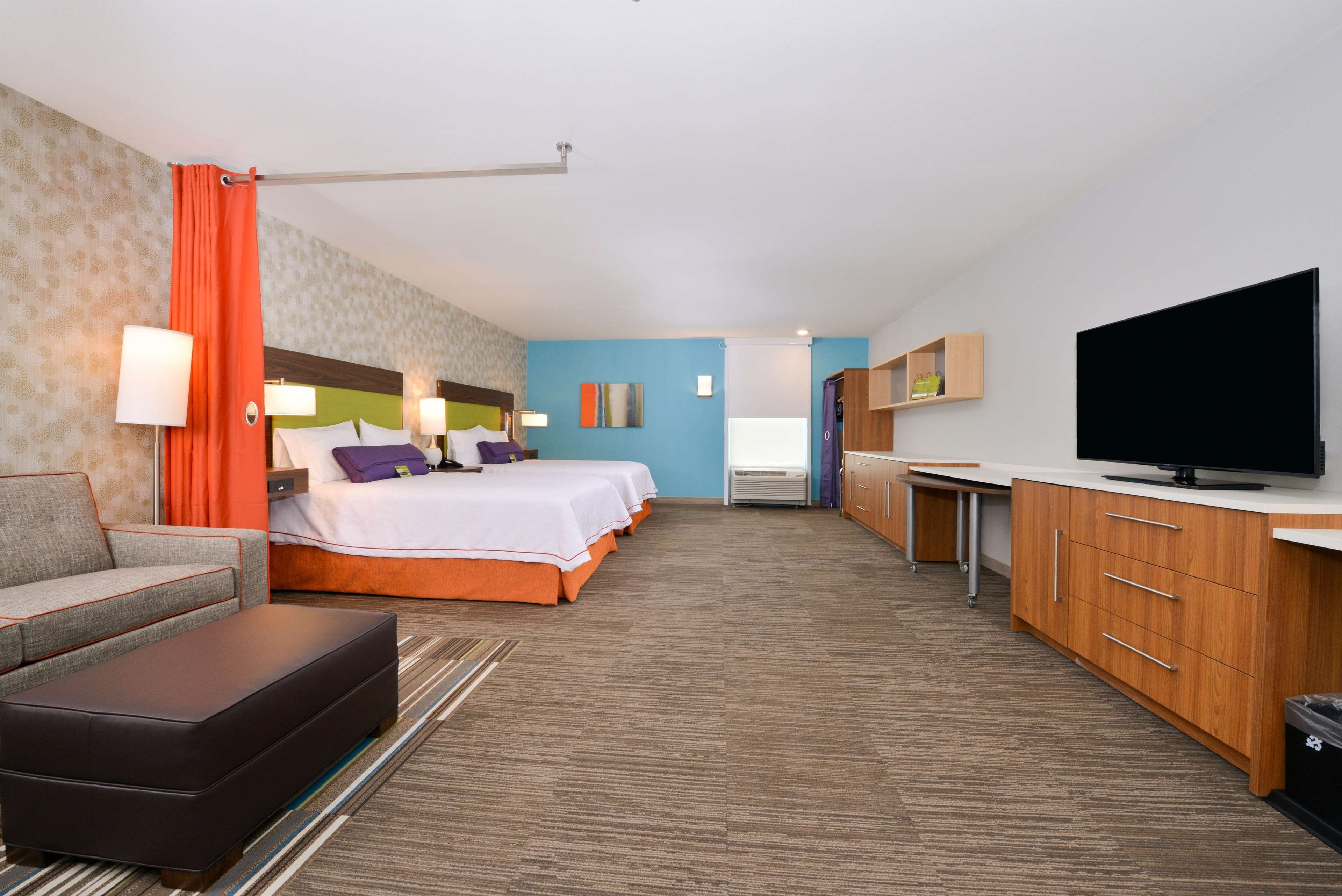 Een hotelkamer met een bed, een slaapbank, een televisie en een kitchenette.