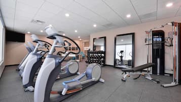 A gym with treadmills, a bench, dumbbells, and weight machines.