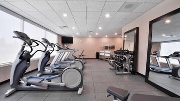 A gym with treadmills, a bench, and a mirror.