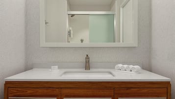 A bathroom with a white sink, wooden vanity, and a large mirror.