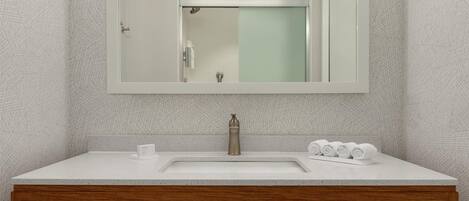 A bathroom with a white sink, wooden vanity, and a large mirror.