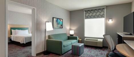A hotel room with a bed, a sofa, a desk, and a TV.