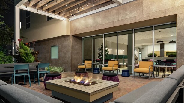 An outdoor patio with a fire pit, seating, and a view of the building's interior. - Home2 Suites by Hilton Houston Energy Corridor (Houston)