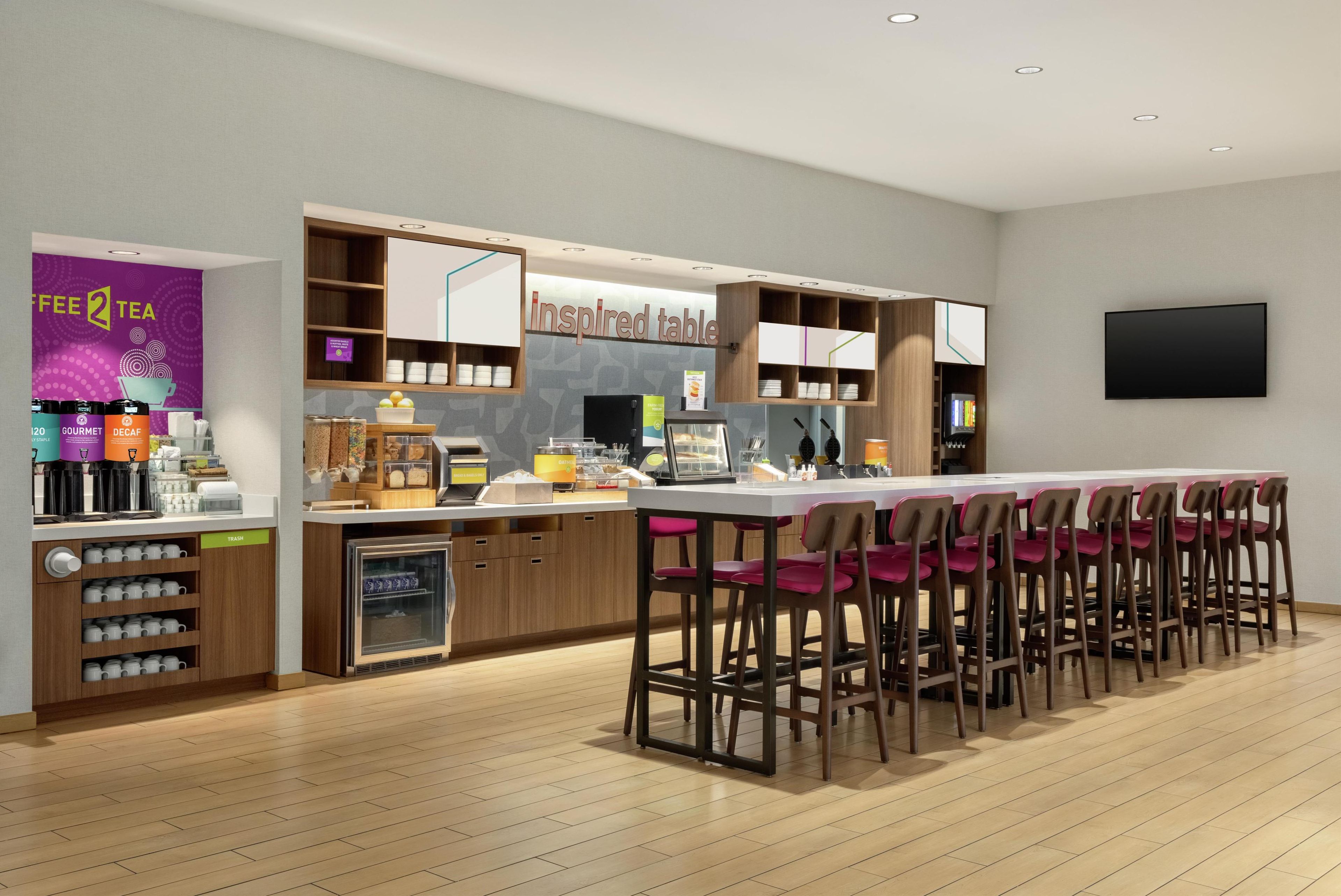 Un café moderno con una zona de bar, una máquina de café y un letrero que dice 'inspired table'.