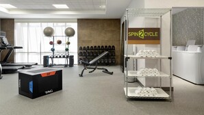 A gym with exercise equipment, a treadmill, and a wall-mounted rack of dumbbells. - Home2 Suites by Hilton Houston Energy Corridor (Houston)