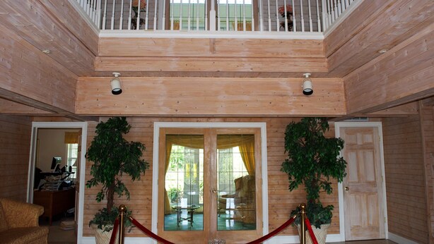 Un intérieur en bois avec un balcon, un escalier et deux portes donnant sur des pièces.