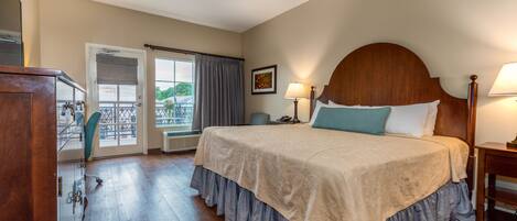 A hotel room with a large bed, a desk, and a view of the outdoors.