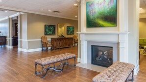A spacious lobby with a fireplace, wooden benches, and framed artwork on the walls.