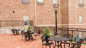 A brick patio with outdoor seating and a street lamp.