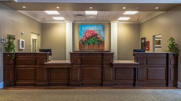 A reception area with a large painting of flowers, a wooden reception desk, and a carpeted floor.