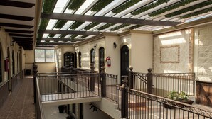 A covered outdoor area with a stone floor, metal railings, and potted plants. - Hotel Villa Bernal (Ezequiel Montes)