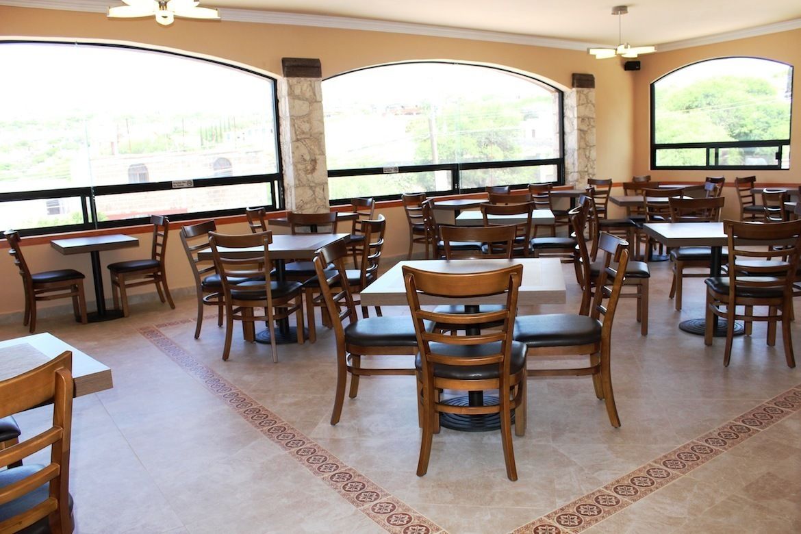 Ein Restaurant mit mehreren Tischen und Stühlen, großen Fenstern mit Blick und einem gemusterten Boden.