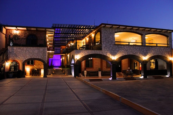 A multi-story building with a stone facade, arched walkways, and outdoor seating areas.