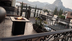 A rooftop terrace with a fire pit, potted plants, and a view of mountains. - Hotel Villa Bernal (Ezequiel Montes)