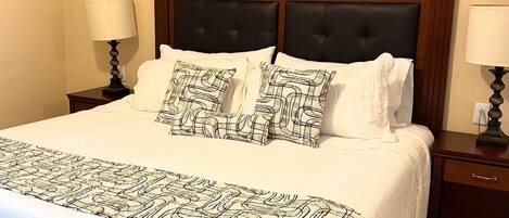 A hotel room with a large bed, two bedside tables, and a wall-mounted artwork.