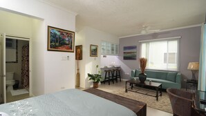 Ein Schlafzimmer mit einem Bett, einem Schreibtisch, einem Stuhl, einer Couch und einem Fenster mit Jalousien.