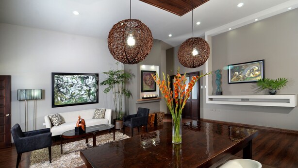 A modern living room with a dark wooden dining table, a white sofa, and a large abstract painting on the wall. - New Kingston Apartment at The Palms (Kingston)