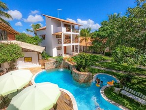 Un complexe hôtelier doté d’une piscine, d’un bâtiment à deux étages et d’une végétation luxuriante.