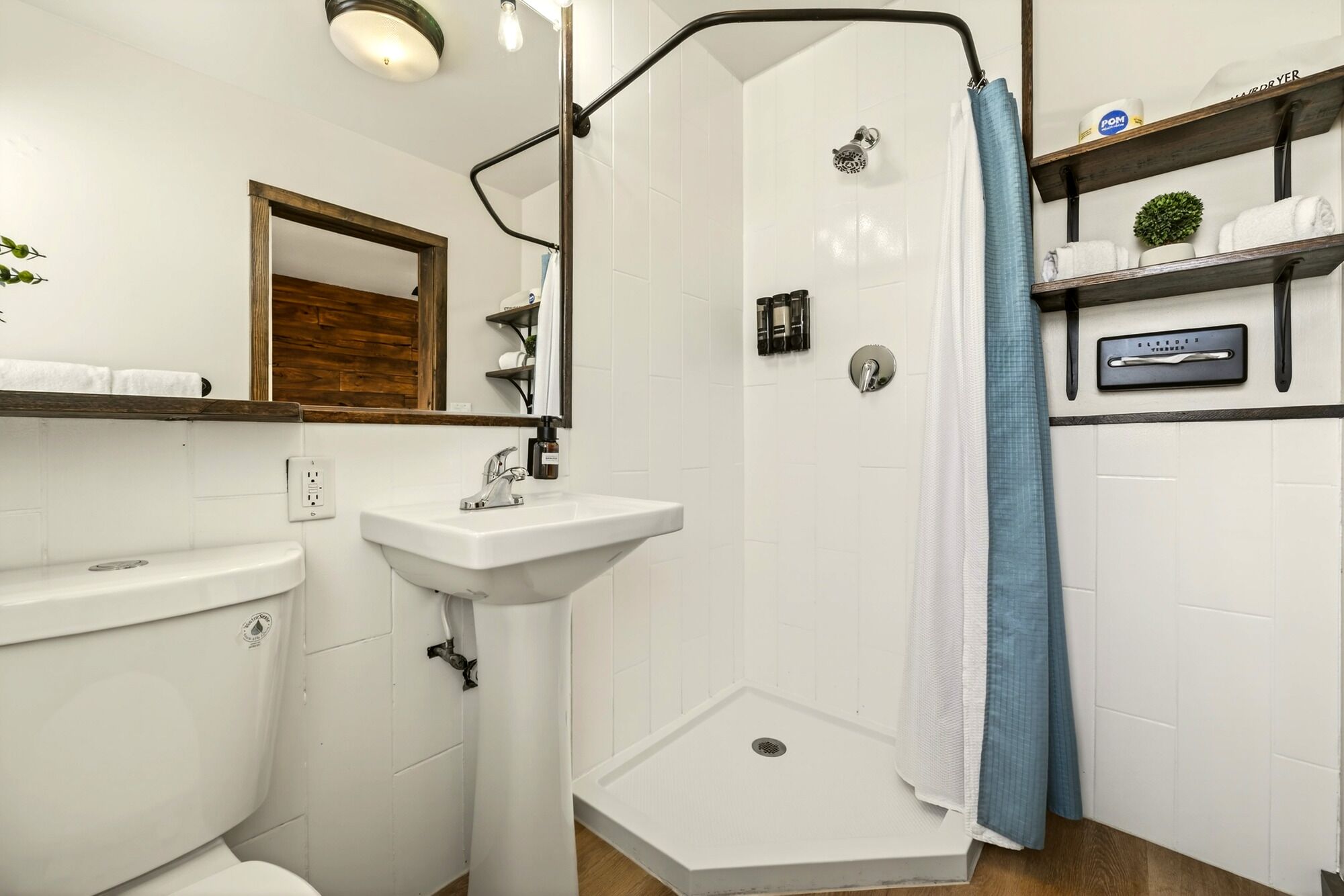 A bathroom with a shower, sink, toilet, and shelves with toiletries.