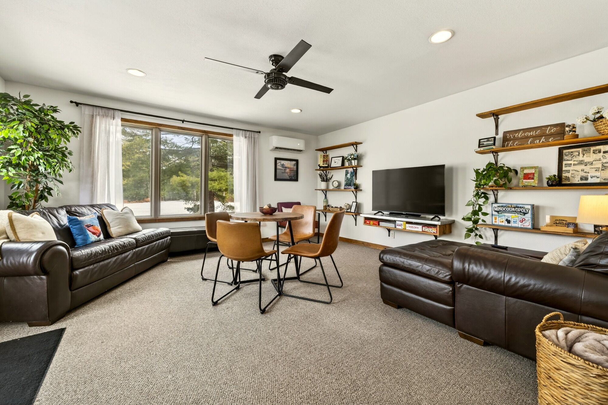A living room with a sofa, chairs, a TV, and a ceiling fan.