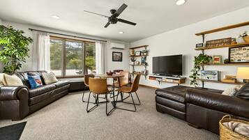 A living room with a sofa, chairs, a TV, and a ceiling fan.