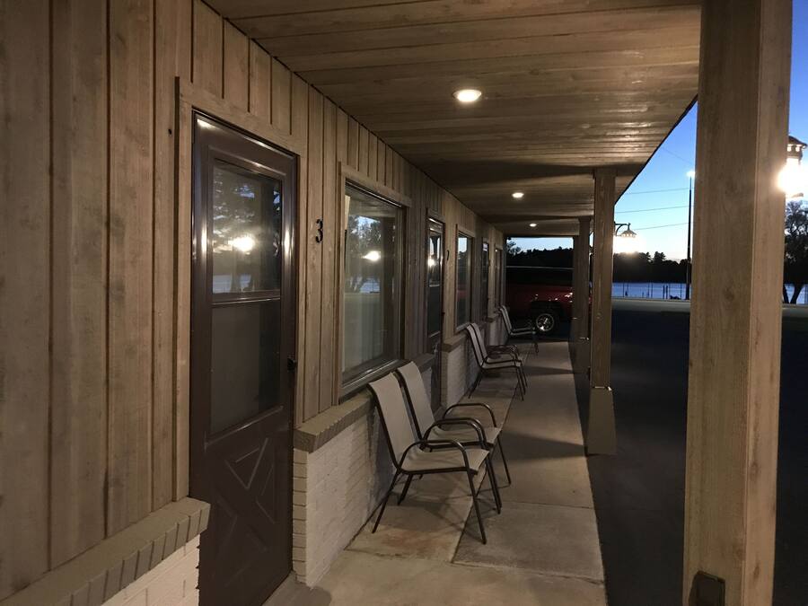 Un espacio al aire libre cubierto con paredes de madera, puertas numeradas y sillas de metal.