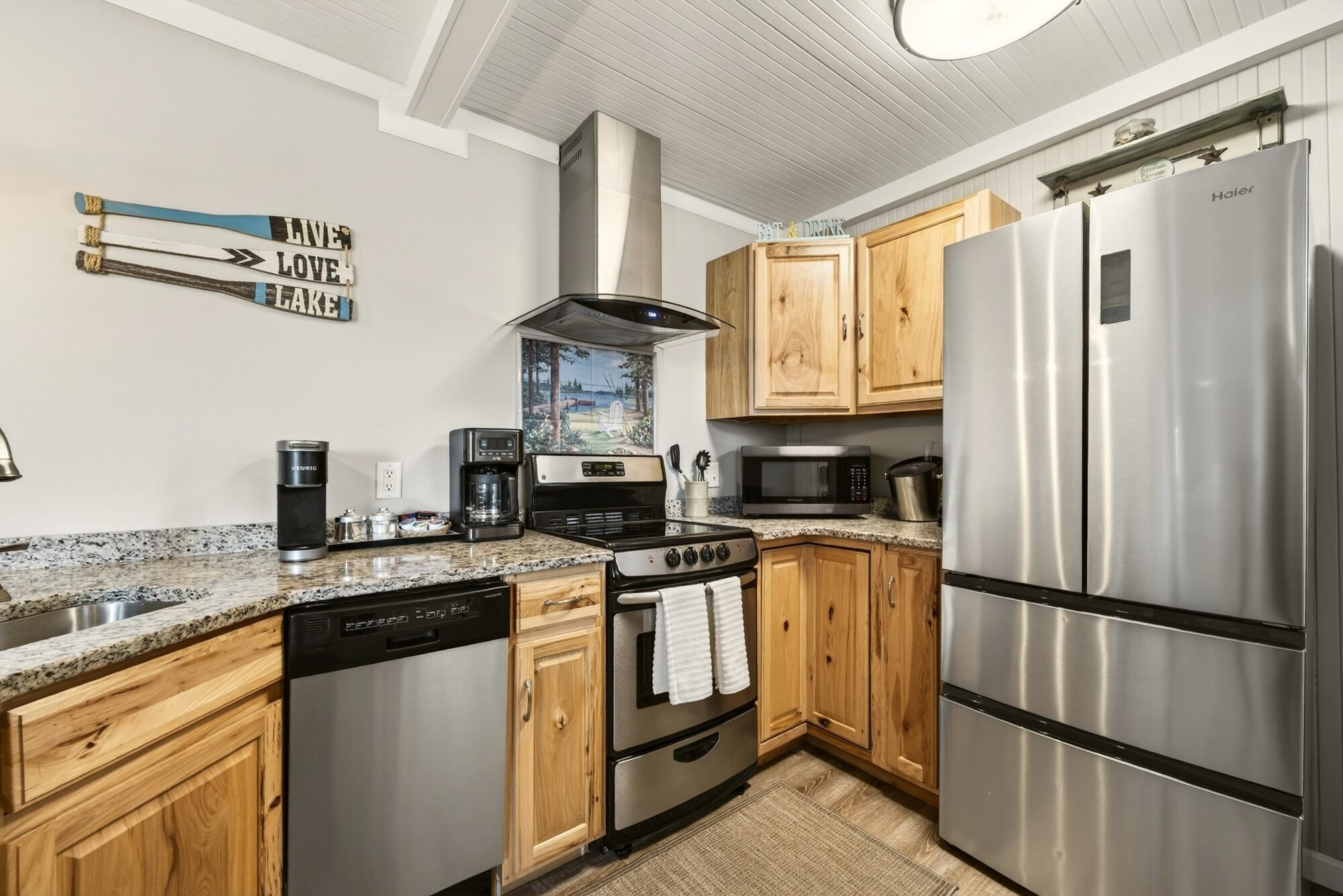 A modern kitchen with wooden cabinets, stainless steel appliances, a coffee maker, and a stove.