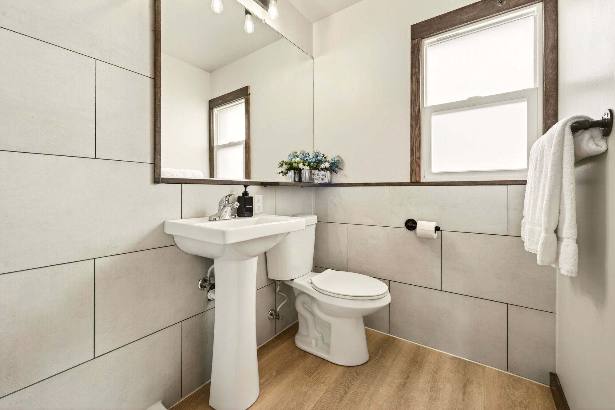 Un baño con lavamanos, inodoro y espejo blancos.