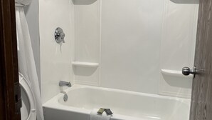 A bathroom with a bathtub, toilet, and shower. - Executive Inn (West Columbia)