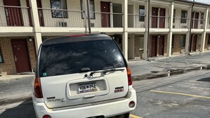 A white SUV parked in a multi-story parking garage with a visible license plate. - Executive Inn (West Columbia)